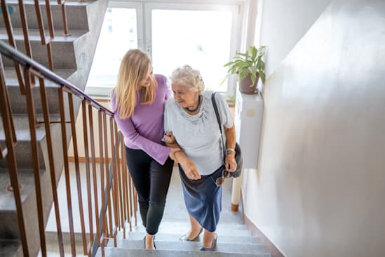 Einer Seniorin wird beim Treppen hinaufsteigen geholfen Einer Seniorin wird beim Treppen hinaufsteigen geholfen