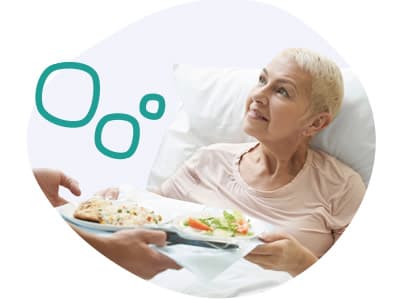Patientin, die ein Tablett mit Essen von einer Pflegekraft gereicht bekommt Patientin, die ein Tablett mit Essen von einer Pflegekraft gereicht bekommt