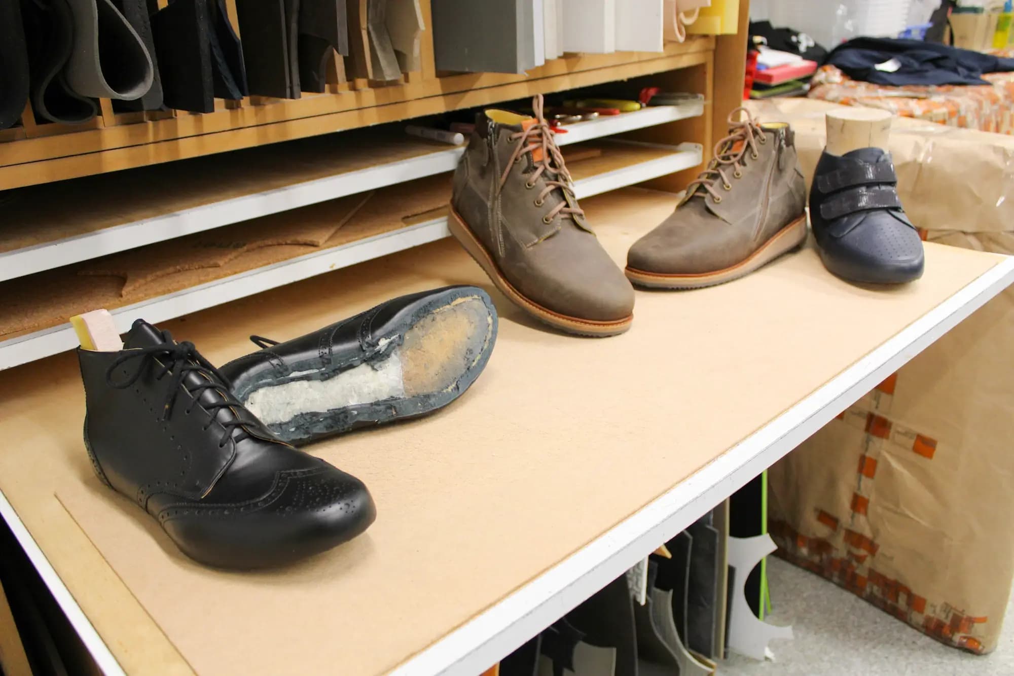 Mehrere Diabetiker-Schuhe in schwarz und braun liegen auf Werkbank Mehrere Diabetiker-Schuhe in schwarz und braun liegen auf Werkbank